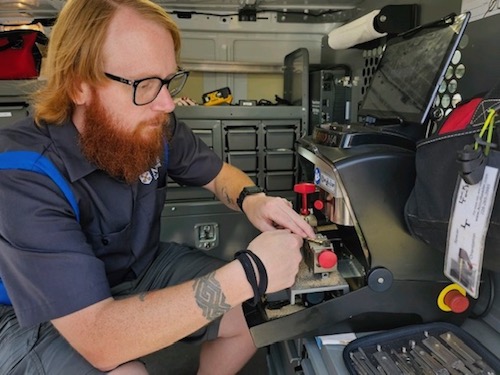 Noble Atlanta locksmith technician duplicating a key using a key cutter inside his locksmith van